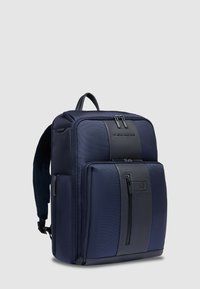 Zaino blu navy realizzato in tessuto strutturato, con pannello in pelle liscia, tasche anteriori con zip e spallacci imbottiti regolabili.