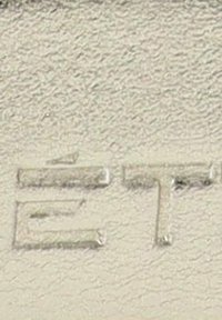 Material texturizado de color beige claro con letras en relieve "E" y "T" en una fuente de bloque. La superficie parece ligeramente reflectante y desigual.