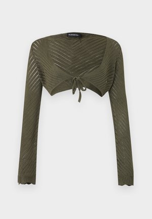 Shrug tricotat scurt, verde măsliniu, cu mâneci lungi, model ajurat chevron și închidere cu fundă frontală.