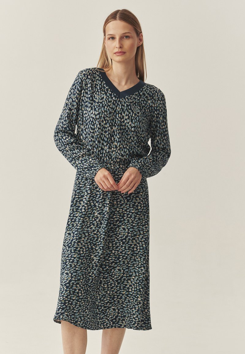 Rochie cu mâneci lungi, de culoare albastru închis, cu decolteu în v formă, având un model texturat cu puncte de culoare bleu deschis și bej. Material moale, cu o lungime medie.