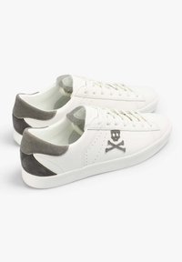 Weiße Ledersneaker mit einer grauen Wildlederfersenlasche, durchbrochenen Details und gesticktem Totenkopf- und gekreuzten Knochen-Logo.