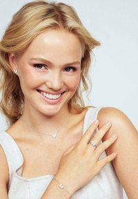 Silversmyckeset med fjärilsmotiv, inklusive örhängen, ett halsband, en ring och ett armband, visat mot en ljus bakgrund.