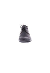 Chaussure en cuir noir avec un bout rond, texture lisse et système de laçage. Présente des coutures discrètes et un accent rouge sur les lacets.
