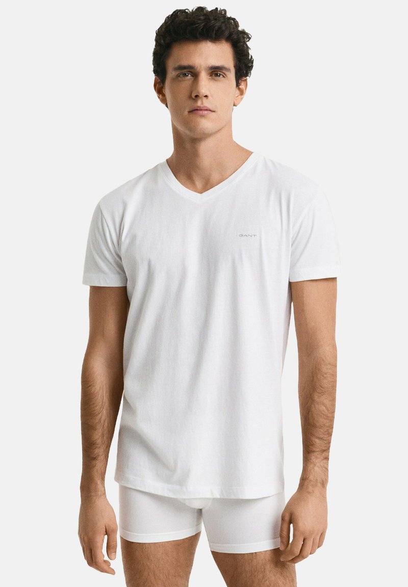 Hvid bomulds v-hals t-shirt, korte ærmer, afslappet pasform; vist på en mandlig model iført hvide boxershorts, minimal branding på brystet.