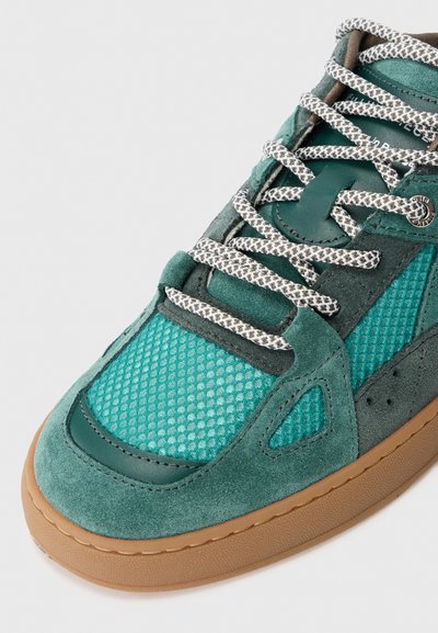Teal semsket og mesh sneakers med en teksturert overdel, kontrasterende mørke detaljer og runde lisser med rutete mønster. Gummisåle.