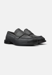 Svarta läderloafers med ett brett band över vristen, texturerad gummisula och rundad tådesign.