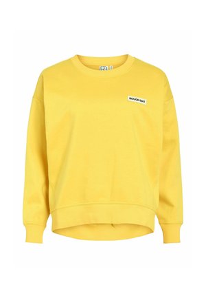 Sweatshirt jaune à manches longues avec col ras du cou, poignets et ourlet côtelés, comportant un petit patch blanc avec l'inscription "ROUGE EDIT" sur la poitrine gauche.