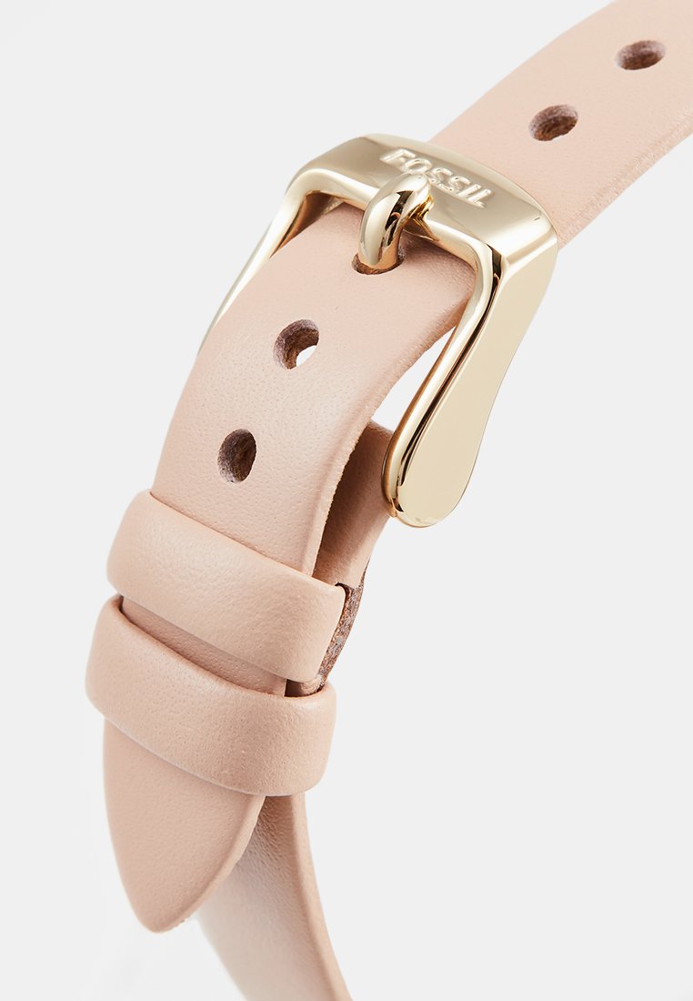 Bracelet de montre en cuir rose clair avec boucle en métal doré et trous réglables pour le sizing. Présente une texture lisse et un design minimaliste.