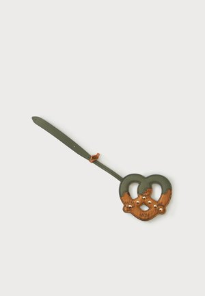 Llavero de cuero verde y marrón con forma de pretzel, tachuelas doradas y una correa ajustable sobre un fondo liso.