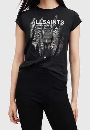 Femme portant un t-shirt noir à manches courtes avec un graphisme de visage de tigre et le texte "ALLSAINTS" sur la poitrine.
