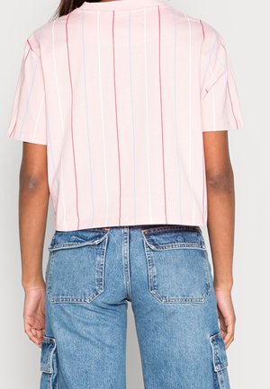 Camiseta corta rosa con Rayas verticales rojas y azul claro; mangas cortas; combinada con pantalones cargo de mezclilla azul de tiro alto.