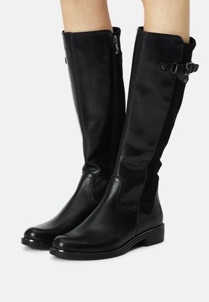 Bottes montantes en cuir noir à finition lisse, avec fermetures éclair latérales, panneaux élastiques et talon bas empilé. Agrémentées d'un détail boucle.