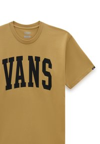 T-shirt dorata con maniche corte, caratterizzata da un grande logo nero "VANS" sul petto. Realizzata in morbido tessuto di cotone. Vestibilità classica.