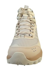 Beżowy but sportowy z teksturowaną siateczkową cholewką, kontrastową jasnobrązową podeszwą i pewnym systemem sznurowania z metalowymi elementami oraz wzorami w kratkę.