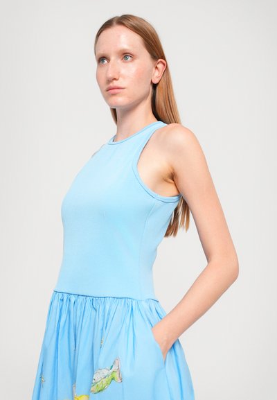 Top senza maniche azzurro chiaro con una texture a costine, abbinato a una gonna blu fluente con motivi di pesci. Design casual e comodo.