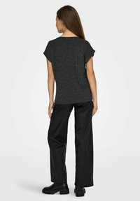 Sort top med korte ærmer og tekstureret udseende, kombineret med løstsiddende sorte bukser og kraftige sorte støvler. Enkel, afslappet stil.