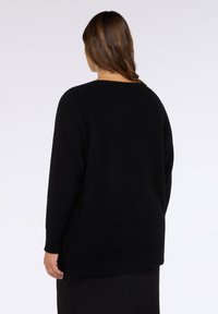 Schwarzer übergroßer Pullover mit entspanntem Schnitt, weitem Ausschnitt und gerippten Bündchen, aus einem weichen, strukturierten Stoff gefertigt.