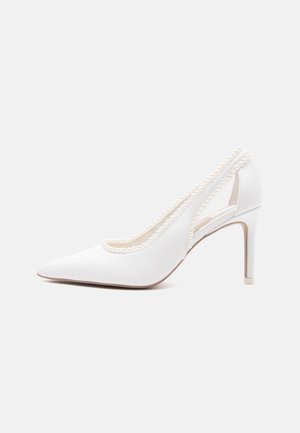 Witte spitse hoge hak met parelranddetail langs de randen en uitgesneden zijkanten, bekeken vanaf de buitenkant.