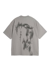 Jasnoszary, oversize T-shirt z abstrakcyjnym czarnym wzorem natryskowym i małymi srebrnymi ćwiekami na środku pleców.