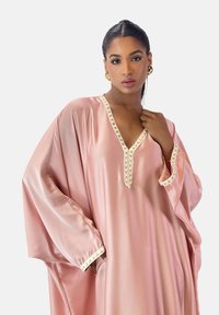 Rosa satin kaftan med V-udskæring og dekorativ cremefarvet kant, med brede ærmer og en glat tekstur.