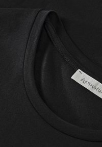Svart bomull t-shirt med rund halsringning, slät textur och en synlig etikett med "hessnatur" tryckt.