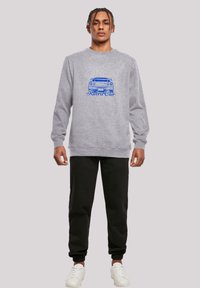 Gray sweatshirt made of fleece, featuring a blue retro car graphic and "Retro Car" text. Paired with black joggers and white sneakers.