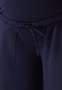 Mörkblå byxor med en mjuk textur, med en elastisk midja och en knytbar dragsko för justerbarhet.