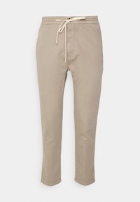 Beige katoenen broeken met een trekkoord in de taille, rechte pijpen en zijzakken. Glad materiaal met minimale stikseldetails.