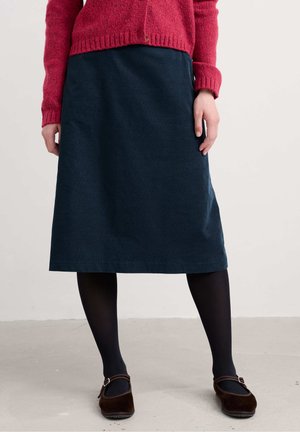Dark blue midi skirt made of smooth fabric, paired with black tights and brown suede shoes. A red textured sweater complements the outfit.