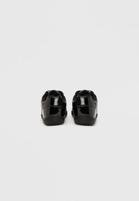 Μαύρα λουστρινά παπούτσια με κομψό, στρογγυλεμένο σχέδιο. Υφή στο τακούνι και μαλακές ελαστικές σόλες προσφέρουν άνεση και κράτημα.