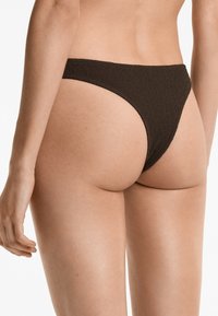 Chiloți de bikini texturat, de culoare maro, cu un design tăiat înalt. Are curele subțiri pe laterale și o acoperire minimă pe spate. Finisaj neted.