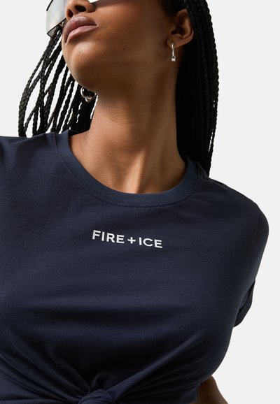 Tmavě modré tričko vyrobené z měkké látky, které má kulatý výstřih, uzlový design v přední části a bílé logo "FIRE+ICE".