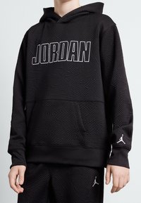 Felpa nera con cappuccio e motivo testurizzato, con logo "JORDAN" in bianco, tasca a marsupio e iconico logo Jumpman sulla manica.
