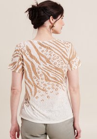 Leichtes Kurzarmhemd mit einem beigen und cremefarbenen Tierdruckdesign, das verschiedene Streifen und Leopardenmuster zeigt. Weiche, fließende Textur.