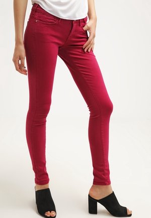 Slim-fit bright red pants worn with black open-toe block heel shoes and a white tucked-in top, shown from waist to feet.