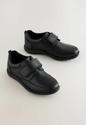 Chaussures en cuir noir avec une finition lisse, bande velcro réglable, bout rond et semelle en caoutchouc. Présentent des détails de couture subtils.