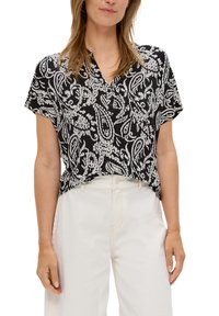 Zwart-wit paisley-gepatrooneerde blouse met korte mouwen en een notch-kraag, gecombineerd met lichtgekleurde hoge taille broeken. Zachte stoftextuur.