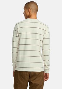 Ecru lange mouwen shirt met roestkleurige horizontale strepen, gemaakt van ribgebreide stof, met een ronde halslijn en rechte onderkant.