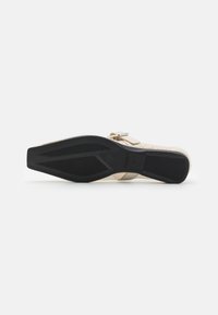 Light beige sandal with a woven upper, adjustable strap closure, and a black textured rubber sole. Designed for comfort and breathability.
