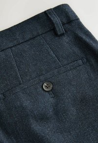 Námořnické kalhoty v herringbone vzoru s texturovanou vlněnou směsí, s jedním černým knoflíkem a detailem kapsy na zadní straně.