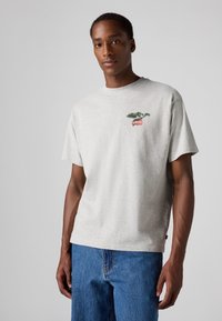 T-shirt en coton gris avec un col rond et des manches courtes, arborant un graphique coloré du logo Levi's sur la poitrine et une coupe décontractée.