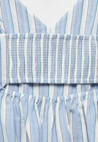 Blue and white striped fabric with a smocked bodice. Features vertical lines and subtle textures. V-neck design with gathered hem edges.