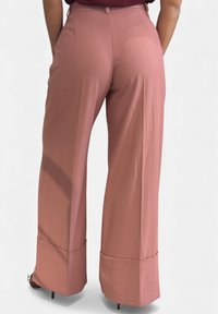 Pantaloni a gamba larga in tessuto rosa chiaro con una texture liscia. Presentano una vita alta e orli piegati, abbinati a tacchi a spillo.