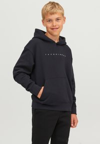 Sötétkék kapucnis felső elülső zsebbekkel, rugalmas mandzsettákkal, és fehér "JACK & JONES" felirattal. Puha anyagból készült, díszített húzókás kapucnival.