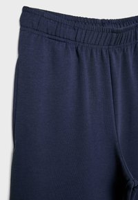 Pantaloni con elastico in vita di colore blu navy, realizzati in morbido tessuto a maglia con cuciture visibili e superficie liscia.