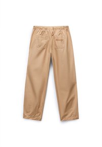 Beige, lette, løstsittende bukser med elastisk liv, to baklommer, som har subtile sømdetaljer og en glatt tekstur.