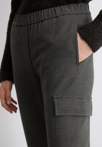 Pantaloni grigi testurizzati con vita elastica, tasche laterali e una tasca cargo sulla coscia, caratterizzati da un delicato motivo.