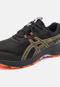 Black athletic shoe with a textured mesh upper, orange and grey accents, rugged sole, and lacing system for secure fit.