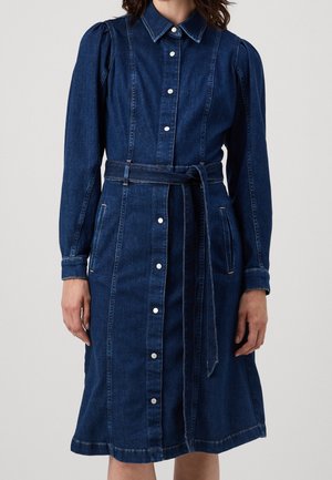 Denimmekko, jossa on pitkät hihat, kauluksellinen kaulus, nappikiinnitys edessä, vyötärölle kiristettävä vyö, sivutaskut ja polvimittainen A-linjainen leikkaus tummansinisessä.