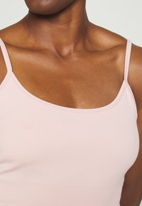 Camisola rosa de alças finas com decote quadrado, apresentando uma textura suave e um design justo.